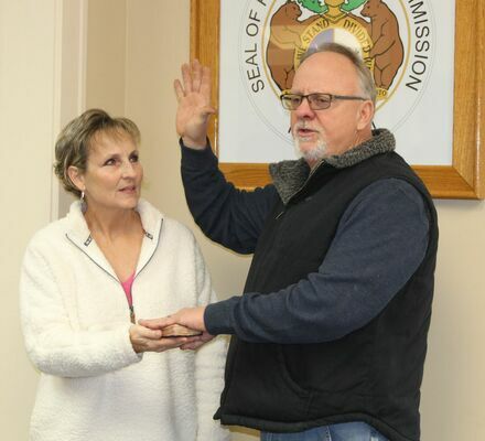 John Lake, re-elected Western District Commissioner, is sworn in with his wife, Sharon, holding the bible.