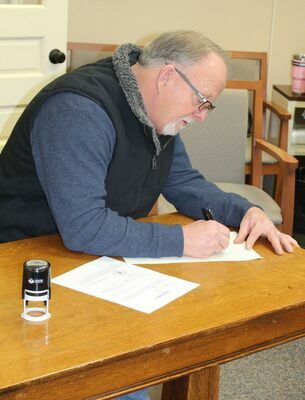 Western District Commissioner, John Lake completes paperwork after being sworn in.